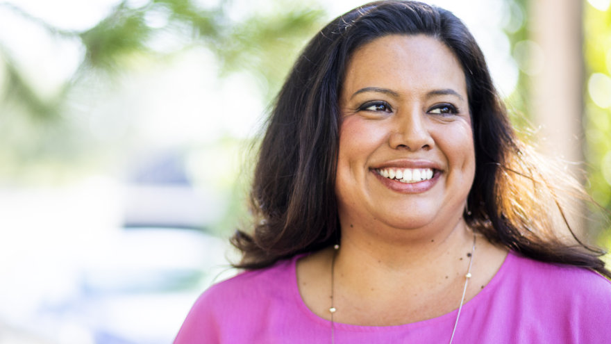 A woman outside smiling as she looks off into the distance.