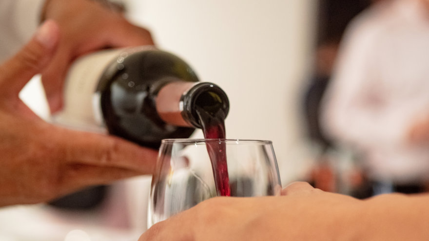 Event attendee having their wine glass filled.