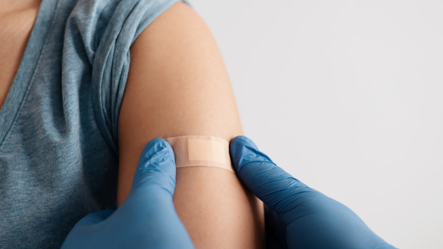 A nurse placing a bandage on a patient's arm.