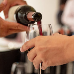 Volunteer pouring wine into an event attendee&#39;s glass.