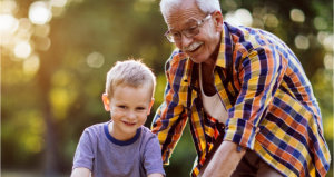 Grandfather helping his grandchild to ride a bicycle.